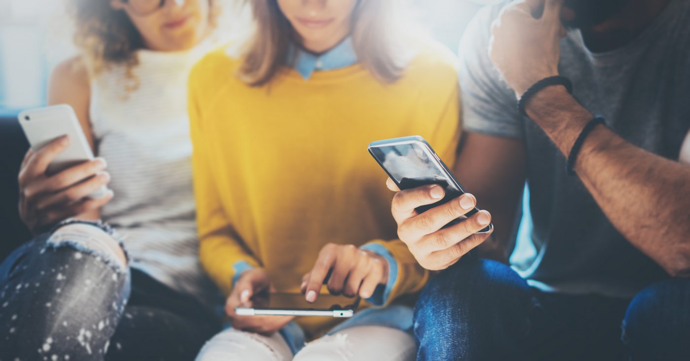 Three people sat next to each other looking at their phones